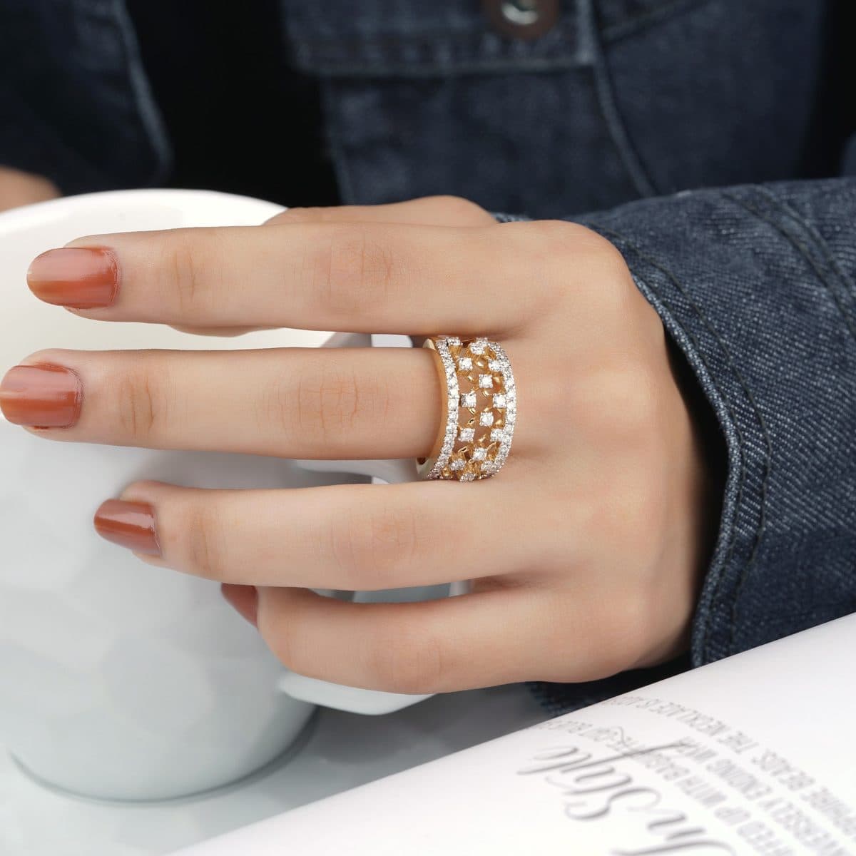 Mano con anillos dorados sosteniendo una taza